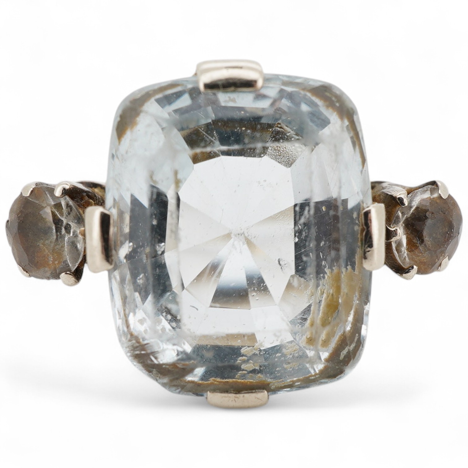 A mid 20th century white metal and single stone cushion cut blue topaz set dress ring, with two stone topaz set shoulders, size R.